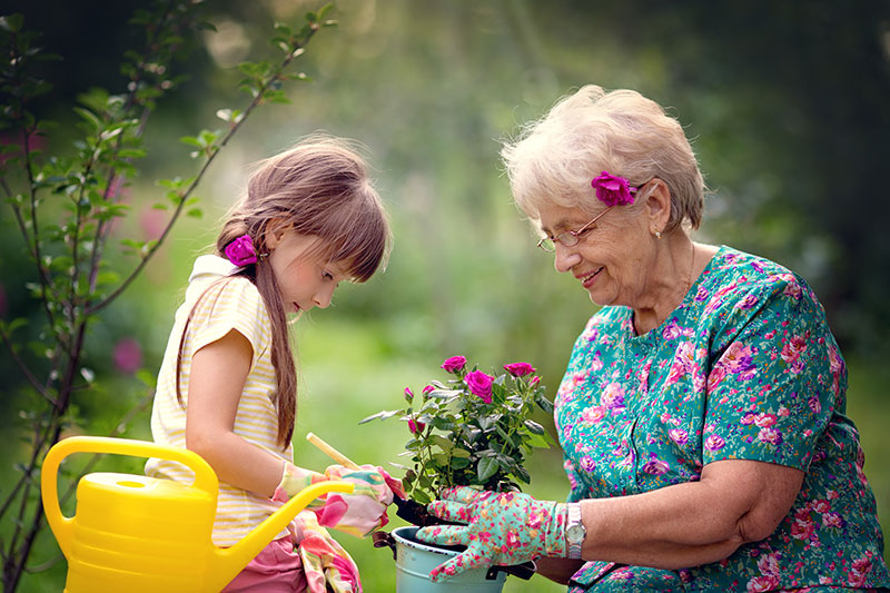 a child and an elderly woman work in the garden